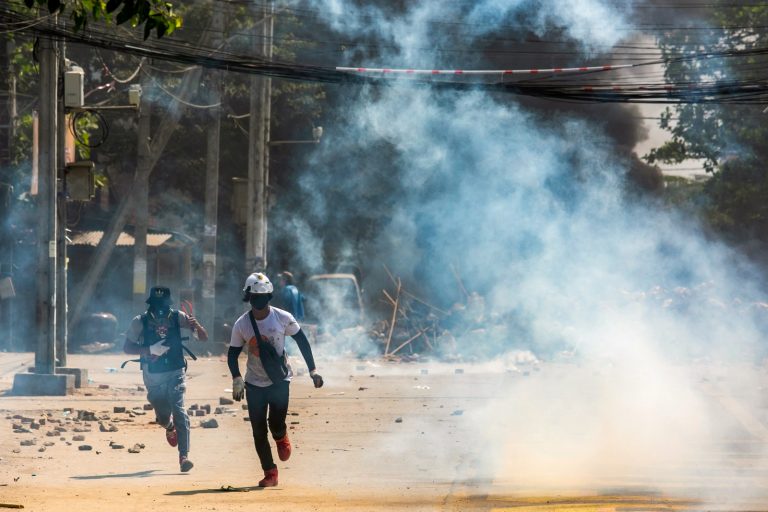 Protesters run as tear gas is fired during a crackdown by security forces on a demonstration against the military coup in Yangon's Thaketa Township on March 19, 2021. (AFP)
